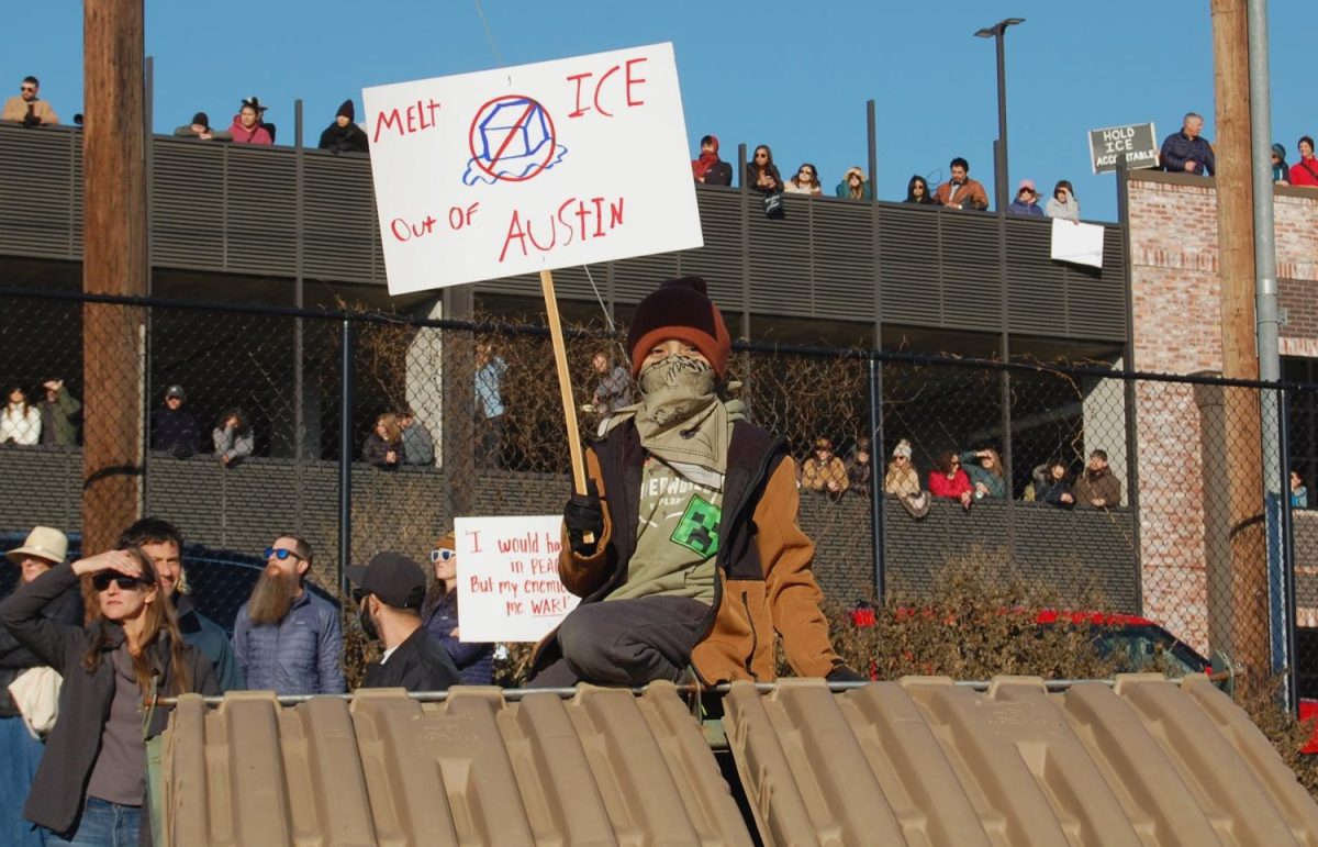 A young boy sits atop a dumpster to see over a crowd of protestors during a demonstration in East Austin Saturday.