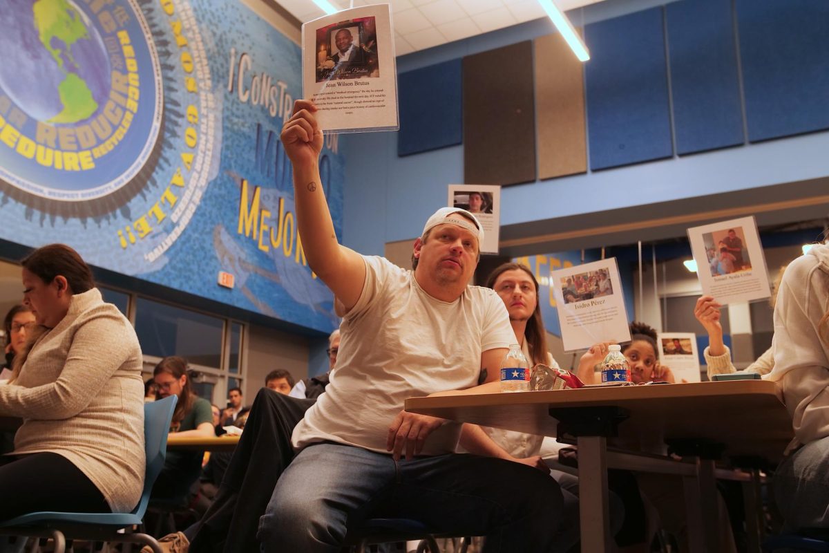 Robert Saulter, a Travis County Public Defender, holds a photo of a man who died in I.C.E. custody during a town hall at Govalle Elementary School in Austin, Texas, Feb. 7th, 2026.